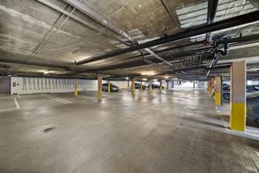 Los Angeles apartment for rent - A spacious parking garage with concrete floors and yellow poles.