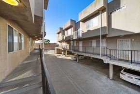 Los Angeles apartment for rent - A car is parked in a parking lot between two buildings.