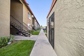 San Bernardino apartment for rent - A narrow alley between two buildings with a metal railing on the left.