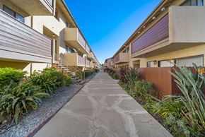 Van Nuys apartment for rent - A concrete pathway leads through a row of modern apartment buildings.