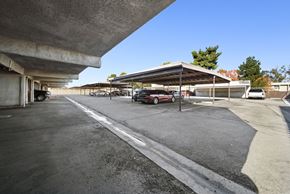 Palmdale apartment for rent - A parking lot with a red car parked in the shade.