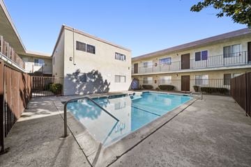 Palmdale apartment for rent - A swimming pool in front of a building with a blue sky in the background.