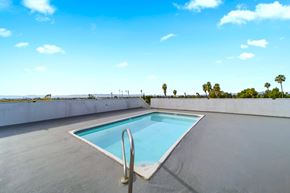 Panorama City apartment for rent - A swimming pool on a rooftop with palm trees in the distance.
