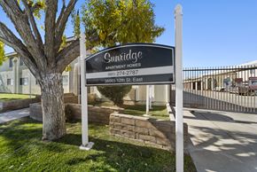 Palmdale apartment for rent - A sign for Sunridge Apartment Homes stands in front of a tree.