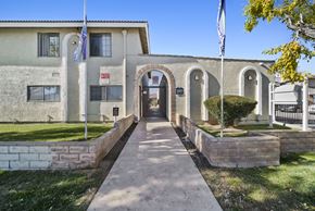 Palmdale apartment for rent - A building with a flag on top and a gate in front.