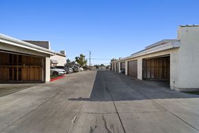 Palmdale apartment for rent - A long, empty parking lot with cars parked on the side.
