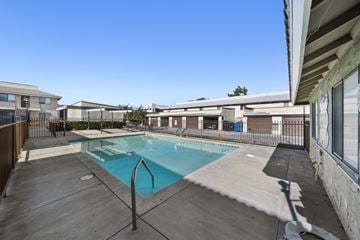 Palmdale apartment for rent - A swimming pool surrounded by a concrete deck and a metal fence.