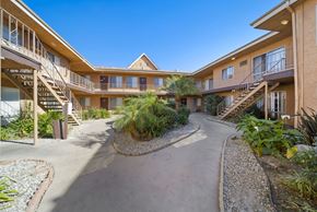 Van Nuys apartment for rent - A courtyard with a pathway and plants in front of apartment buildings.