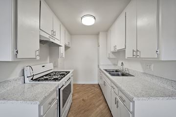 Van Nuys apartment for rent - A kitchen with white cabinets and granite countertops.