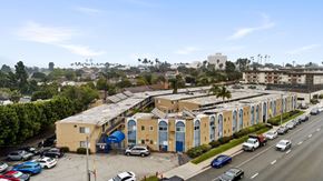 Long Beach apartment for rent - A parking lot with cars and a yellow building with blue doors.