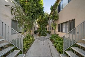 Reseda apartment for rent - A pathway leads through a courtyard with a metal fence on either side.