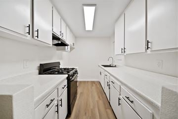 Highland apartment for rent - A kitchen with white cabinets and a black stove top oven.