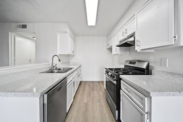 San Bernardino apartment for rent - A kitchen with white cabinets and a black stove top oven.