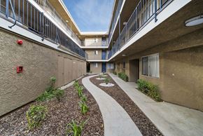 Canoga Park apartment for rent - A concrete pathway leads through a landscaped courtyard between two apartment buildings.