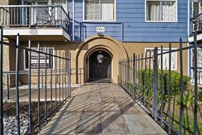 Canoga Park apartment for rent - A blue building with a black gate and a wooden walkway leading to a tunnel entrance.