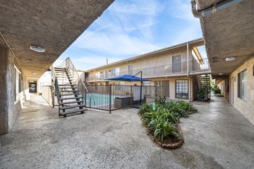 Van Nuys apartment for rent - A concrete courtyard with a pool and a metal fence.