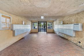 Van Nuys apartment for rent - A long hallway with a brick floor and white lockers on the wall.