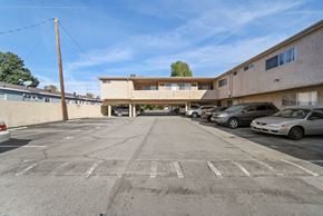 Van Nuys apartment for rent - A parking lot with a building in the background and several cars parked.