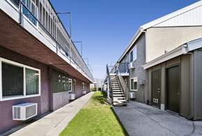 San Bernardino apartment for rent - A long, narrow courtyard between two buildings with a staircase in the middle.