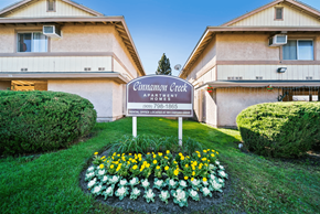 Redlands apartment for rent - A sign for Cinnamon Creek Apartment is in the foreground of a grassy area.