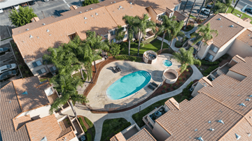 Rialto apartment for rent - A swimming pool surrounded by palm trees and a sandy area.