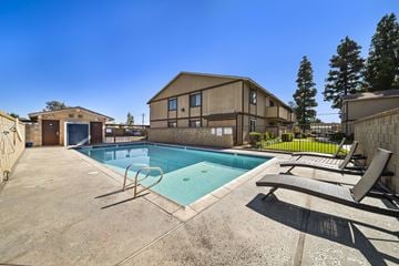 Fontana apartment for rent - A pool with a slide and sun loungers in front of a building.