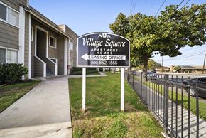 San Bernardino apartment for rent - A sign for Village Square Apartments is in front of a building.