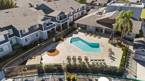 Rialto apartment for rent - A pool surrounded by chairs and a fence in front of a building.