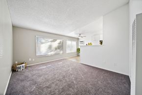 Riverside apartment for rent - A sparsely furnished room with a carpeted floor and a window with blinds.