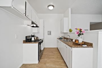 Riverside apartment for rent - A kitchen with white cabinets and a granite countertop.
