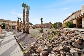 Bullhead City apartment for rent - A rocky landscape with a few trees and a building in the background.