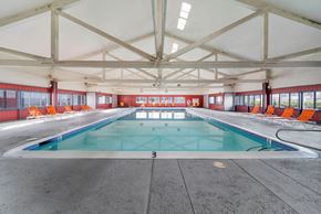 Las Vegas apartment for rent - A large indoor swimming pool with a blue water surface and orange chairs around the pool.