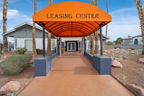 Las Vegas apartment for rent - A leasing center with a bright orange canopy and a pathway leading to it.