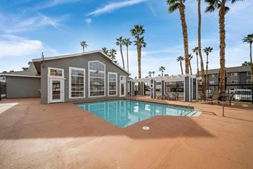 Las Vegas apartment for rent - A pool surrounded by palm trees and a building with a patio.