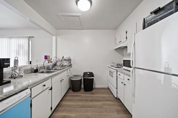 Banning apartment for rent - A kitchen with white appliances and a black trash can.