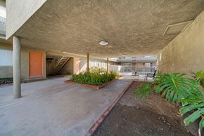 Hawthorne apartment for rent - A concrete building with a red door and plants on the side.