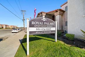 Palmdale apartment for rent - A sign for Royal Palms Apartment Homes stands in front of a building.