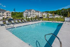 Freeport apartment for rent - A swimming pool surrounded by lounge chairs and apartment buildings in the background.