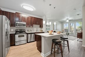 Dallas apartment for rent - A modern kitchen with wooden cabinets and stainless steel appliances at The Atlantic Highland Park, Texas, 75209