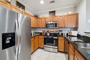 San Antonio apartment for rent - A modern kitchen with wooden cabinets and stainless steel appliances at The Atlantic Stone Oak Apartments, San Antonio