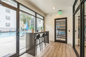 Atlanta apartment for rent - A patio with a bar and chairs is shown with a view of a pool and buildings outside at The Atlantic Loring Heights, Atlanta, Georgia