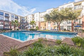 Houston apartment for rent - A swimming pool surrounded by a brick border and palm trees in front of apartment buildings  at The Atlantic Memorial, Houston
