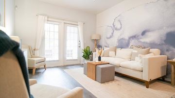 Schertz apartment for rent - A living room with a white sofa, a wooden side table, and a large painting on the wall.