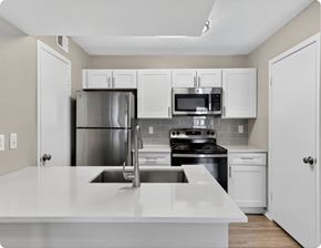 Austin apartment for rent - A kitchen with white cabinets and appliances at Logans Mill, Austin, TX.