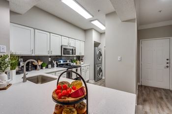 A kitchen with a white countertop and a basket of fruit on it.