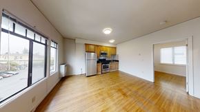 Berkeley apartment for rent - A large empty room with wooden floors and a kitchen area in the background.