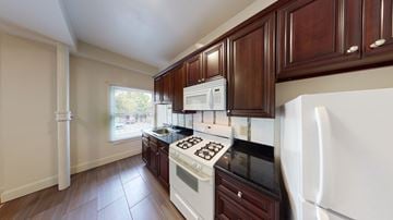 Berkeley apartment for rent - A kitchen with white appliances and dark wood cabinets.