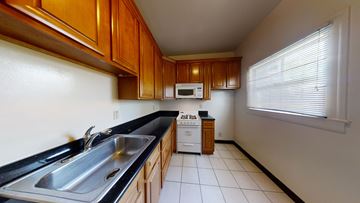 Berkeley apartment for rent - A kitchen with wooden cabinets and a black countertop.