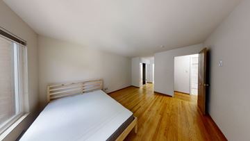 Berkeley apartment for rent - A bedroom with a bed, wooden floors, and a window with blinds.