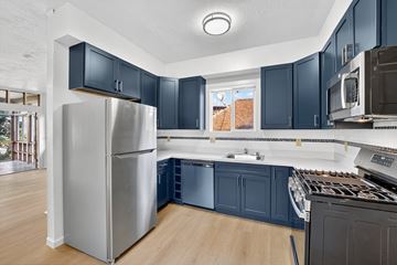 Berkeley apartment for rent - A kitchen with a stainless steel refrigerator and dark blue cabinets.